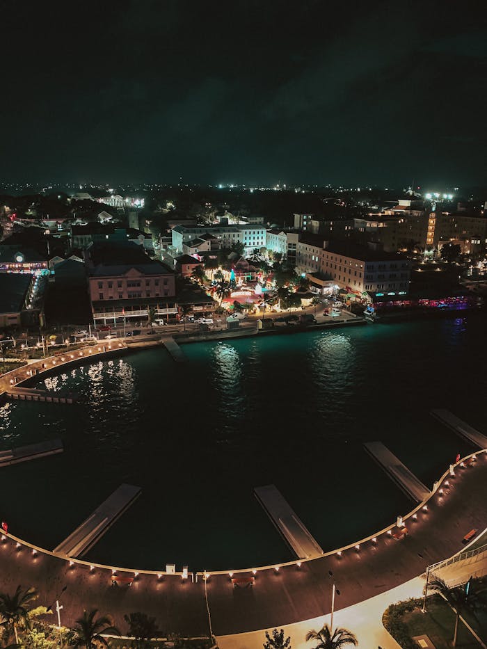 Night aerial view of coastal city illuminated with lights reflecting on water
