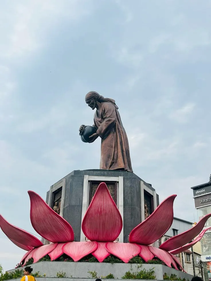 Statue of Sai Baba in Shirdi atop a pedestal with architectural detailing