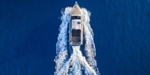 Fast speedboat racing along the open sea leaving white trail. High angle view from drone.